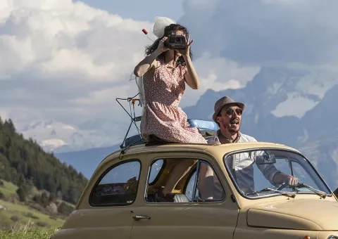 Une femme et un homme debout dans une Fiat 500 décapotée. En toile de fond la montagne © Jean-Pierre Angéi