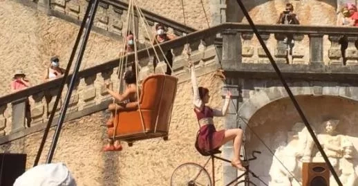 une jeune femme dans un fauteuil suspendu et une jeune femme sur un vélo suspendu avec le château de Vizille en arrière plan