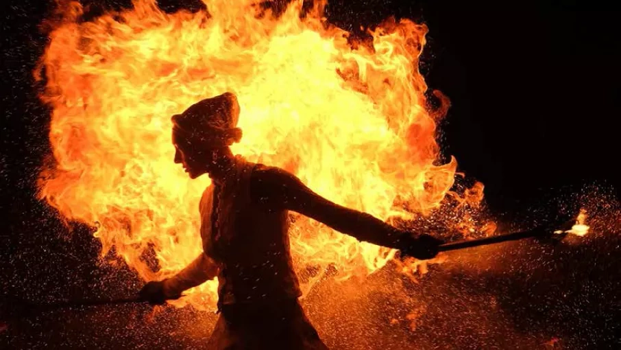 Silhouette d'homme dans la nuit avec bonnet et tenant des torchons devant un grand feu © Augustina Iohan – Chalon dans la rue 2019